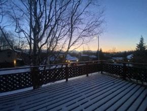 Anchorage house for rent - A snow-covered deck with a railing and bare trees in the background.
