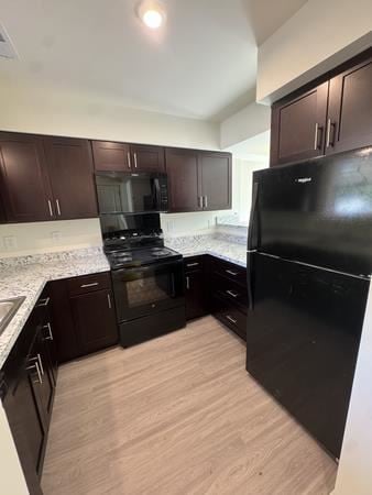 Atco apartment for rent - A kitchen with dark wood cabinets and black appliances.