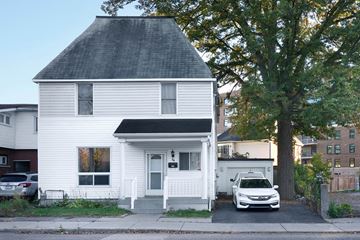 Ottawa apartment for rent - A white house with a black roof and a car parked in front.