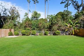 Slidell house for rent - A backyard with a green lawn and trees.