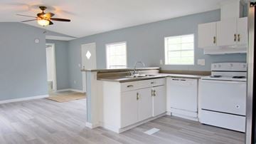 Slidell house for rent - A kitchen with white cabinets and a wooden floor.