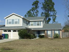 Slidell house for rent - A house with a grey roof and a green trash can in front of it.