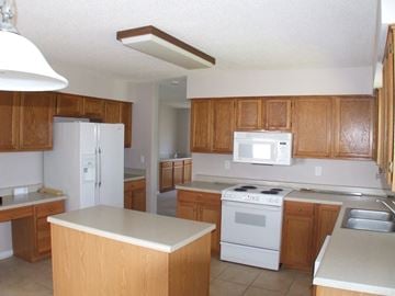 Slidell house for rent - A kitchen with wooden cabinets and white appliances.