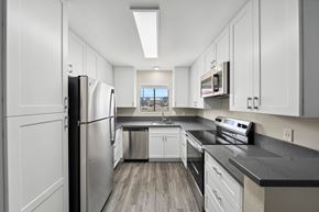 San Diego apartment for rent - A modern kitchen with white cabinets and stainless steel appliances.