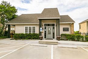 Irving apartment for rent - the front of a tan house with a parking lot and a door