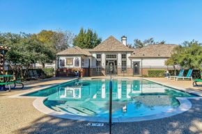 Denton apartment for rent - a swimming pool with chairs and a house in the background