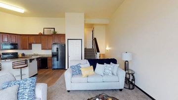 Fargo townhouse for rent - A living room with a grey couch and a kitchen area in the background.
