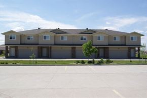 Fargo townhouse for rent - A large, multi-story building with a flat roof and a garage door on each floor.
