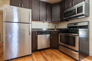 Chicago apartment for rent - an empty kitchen with stainless steel appliances and wooden floors