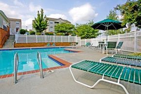 Lynchburg apartment for rent - a swimming pool with green chairs and an umbrella
