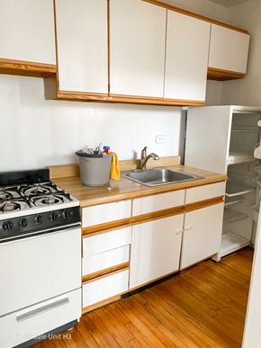 Chicago apartment for rent - a kitchen with white cabinets and a stove and a sink
