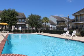 New Orleans apartment for rent - a swimming pool with chairs and houses in the background