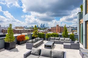 Philadelphia apartment for rent - A rooftop patio with grey furniture and a view of the city skyline.