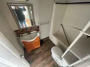 Phenix City apartment for rent - A man is taking a picture of a bathroom with a sink, toilet, and mirror.