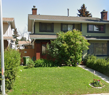 Calgary house for rent - A green lawn in front of a house with a flower bed in the front.