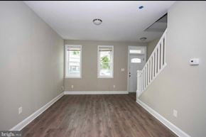 Baltimore house for rent - A spacious room with wooden floors and a staircase on the right side.