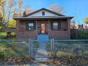 Saint Louis house for rent - a small brick house behind a chain link fence
