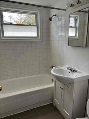 Halifax apartment for rent - A white bathroom with a tub, sink, and mirror.