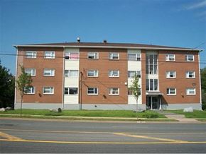 Halifax apartment for rent - A large brick apartment building with a parking lot in front.