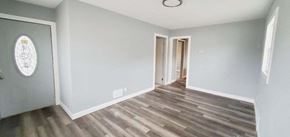Gary house for rent - a renovated living room with wood flooring and a door to a hallway