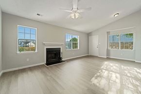Havelock house for rent - A spacious living room with a fireplace and a ceiling fan.