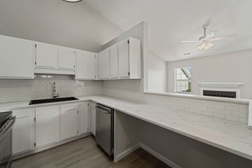 Havelock house for rent - A kitchen with white cabinets and a black fridge.