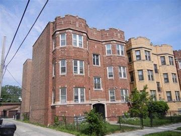 Chicago apartment for rent - A large red brick building with a black gate in front.