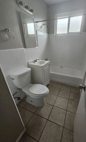 Ontario apartment for rent - A white toilet sits in a small bathroom with a white sink and a mirror.
