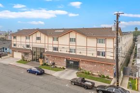 Hawthorne apartment for rent - A blue car is parked in front of a brown building.