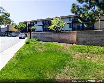 Port Hueneme apartment for rent - A grassy area in front of a building with a wall and trees.