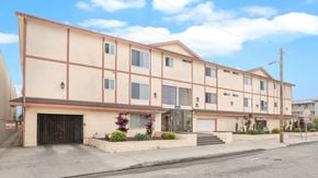 Hawthorne apartment for rent - A building with a red and beige facade has a black gate in front.