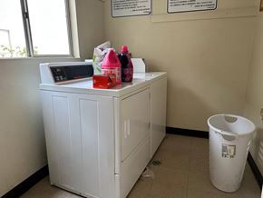 Vista apartment for rent - A white washing machine sits in a room with a trash can and a window.