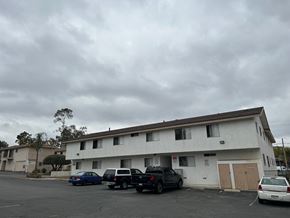 Vista apartment for rent - A parking lot with a white building and cars parked in front.