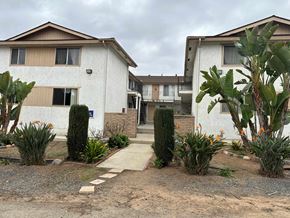 Vista apartment for rent - A white building with a brown roof and a small garden in front.
