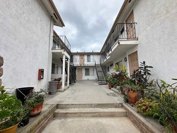 Vista apartment for rent - A courtyard with a white building and potted plants.