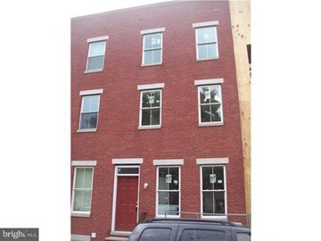 Philadelphia apartment for rent - A red brick building with a black car parked in front.