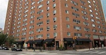 Philadelphia apartment for rent - A tall brick building with many windows and a street in front.