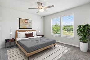 Leander apartment for rent - A bedroom with a bed, a ceiling fan, and a potted plant.