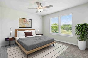 Hutto apartment for rent - A bedroom with a large bed, a ceiling fan, and a view of the outdoors through the window.