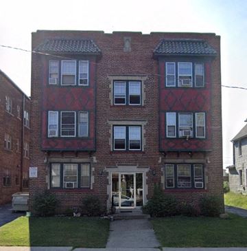 Cleveland apartment for rent - A red brick building with black window frames and a white door.