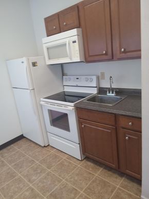 Wasilla apartment for rent - A kitchen with white appliances and brown cabinets.
