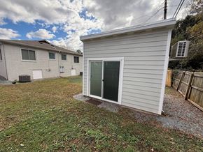 Charlotte house for rent - A small white shed with a green door is situated in a grassy area.