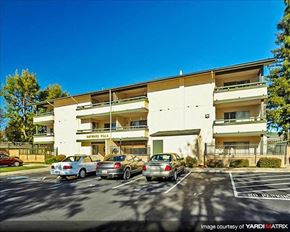 Hayward apartment for rent - A parking lot in front of a multi-story apartment building with cars parked.