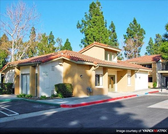 Laguna Niguel apartment for rent - A building with a red tile roof and a white facade with a small tree in front.