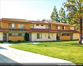 Laguna Niguel apartment for rent - A yellow house with a red tile roof and a green lawn in front.