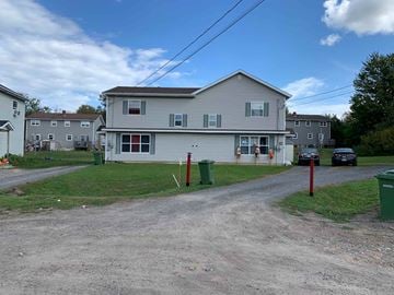 Kentville apartment for rent - A house with a grey roof and a red door is surrounded by other houses.