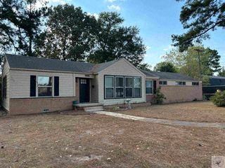 Texarkana apartment for rent - A house with a grey roof and a black door is surrounded by trees.