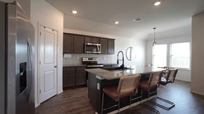 Royse City house for rent - A modern kitchen with dark wood cabinets and a stainless steel refrigerator.