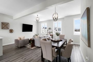 London apartment for rent - A modern living room with a grey sofa, a wooden dining table and chairs, and a television mounted on the wall.