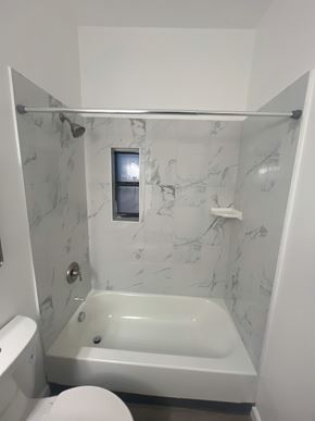 St. Louis apartment for rent - A white bathroom with a marble wall and a white tub.